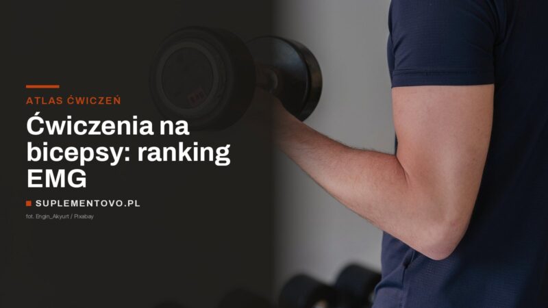 Mężczyzna w ciemnej koszulce ugina ramię z hantlem przy stojaku z hantlami na siłowni