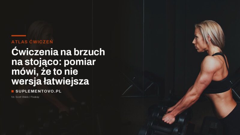 Kobieta stojąca przy stojaku z hantlami w siłowni, sylwetka w pozycji pionowej