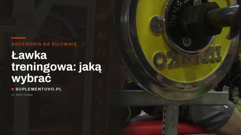 Sztanga z talerzami na stojakach nad czerwoną ławką do wyciskania