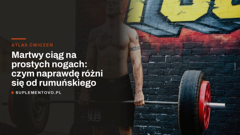 Mężczyzna stojący ze sztangą obciążoną oponami przed murem z graffiti