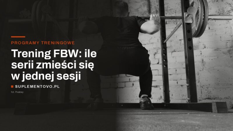 Mężczyzna w dolnej fazie przysiadu ze sztangą w stojaku na siłowni