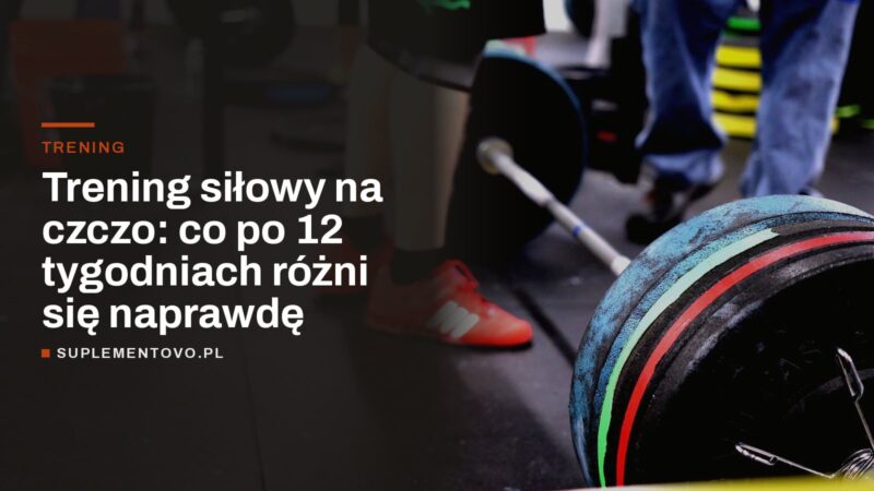 Załadowana sztanga olimpijska na podłodze siłowni, w tle nogi ćwiczących